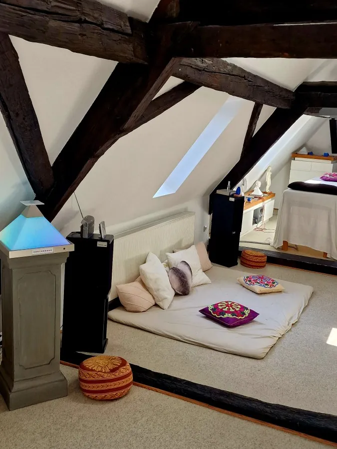 Seminarraum unter Holzbalken im Kompetenz Center Limburg, mit Matten, Kissen und einer leuchtenden Pyramide