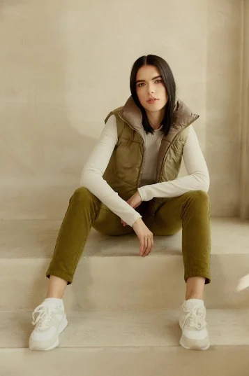 Sophia Elpel sitzt bei einem Shooting in Weste und heller Hose auf einer Stufe