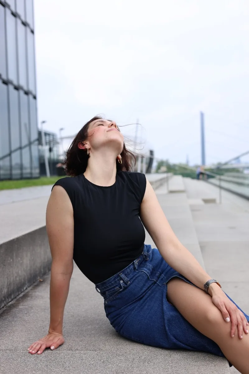 Sophia Elpel sitzt draußen auf einer Treppe und blickt lachend nach oben